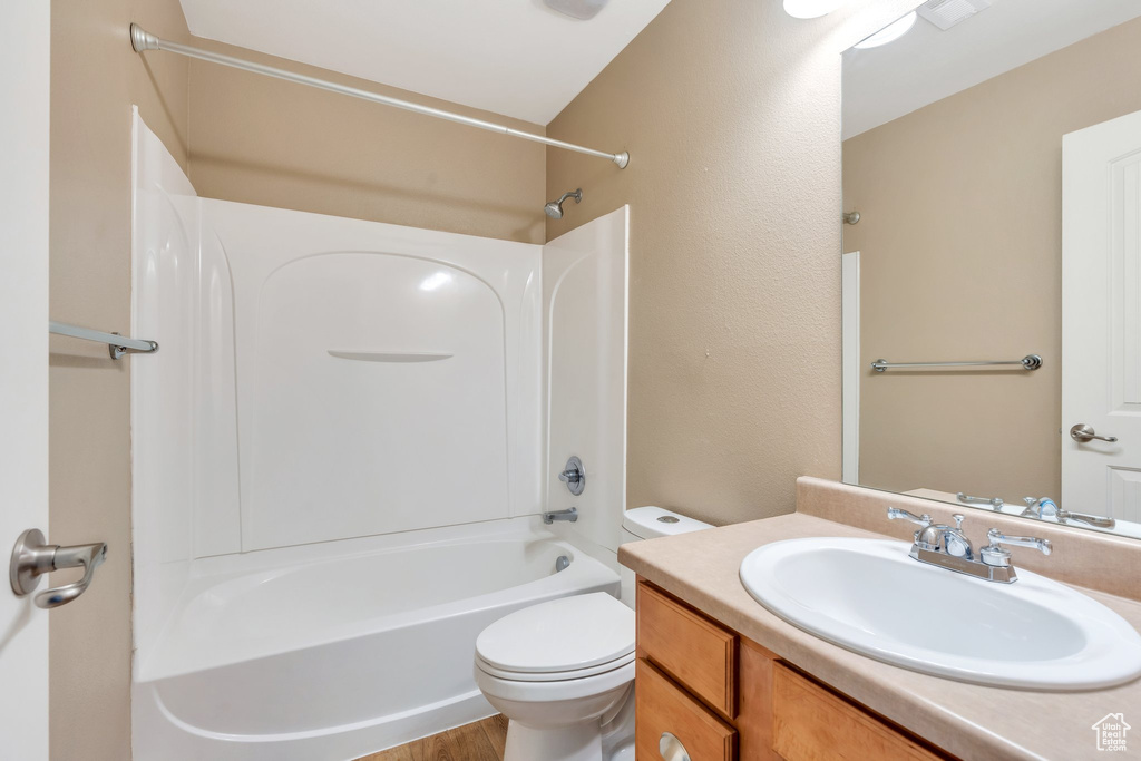 Full bathroom with vanity, toilet, shower / washtub combination, and wood finished floors