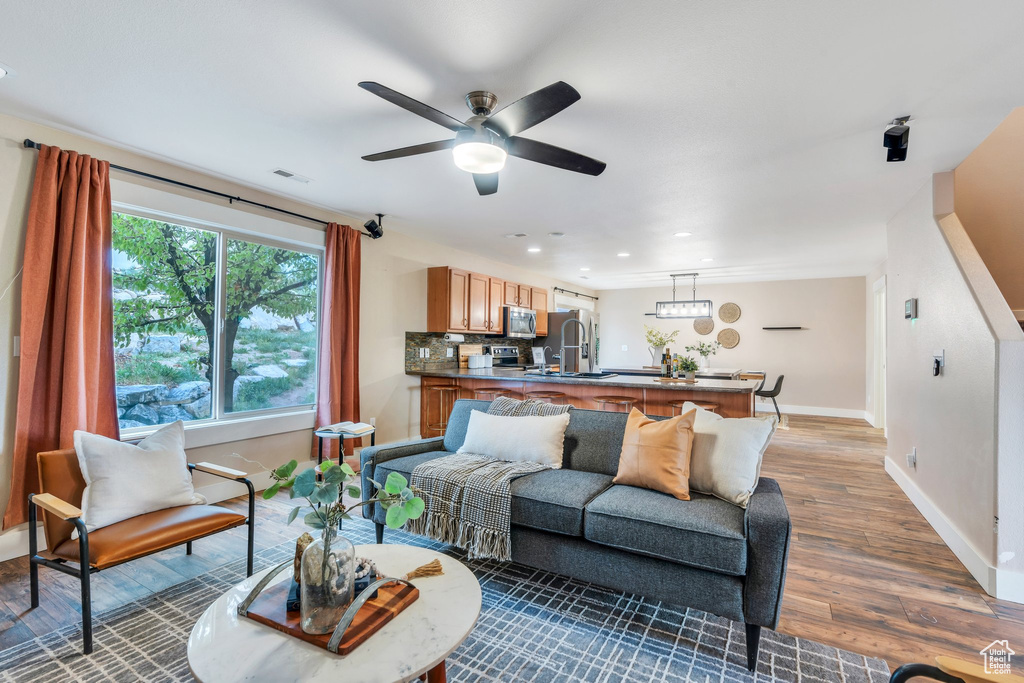 Living area with light wood-type flooring, visible vents, recessed lighting, ceiling fan, and baseboards