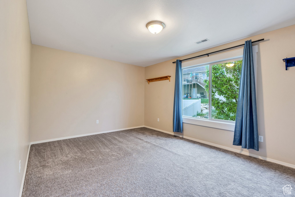 Spare room featuring carpet, visible vents, and baseboards
