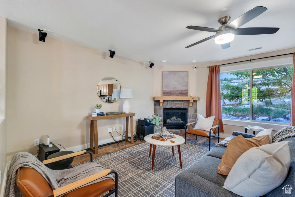 Living room with baseboards, ceiling fan, a stone fireplace, and visible vents