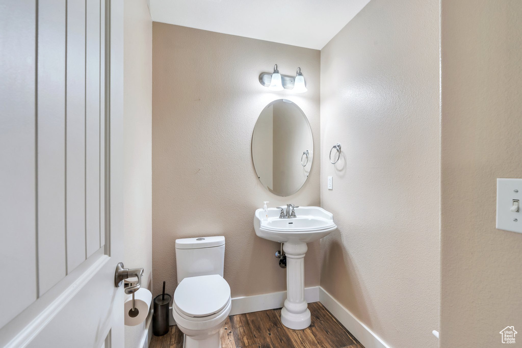 Bathroom featuring a sink, toilet, baseboards, and wood finished floors