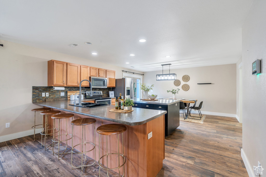 Kitchen with a peninsula, baseboards, dark wood-type flooring, and appliances with stainless steel finishes