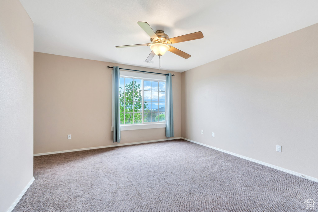 Carpeted spare room featuring baseboards and ceiling fan
