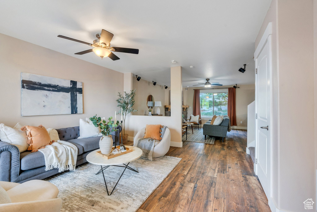 Living area with baseboards, wood-type flooring, and ceiling fan