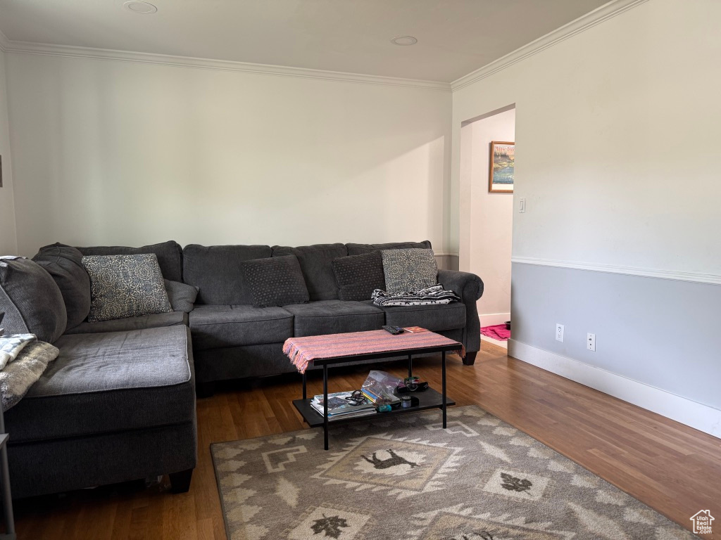 Living room with crown molding, wood finished floors, and baseboards