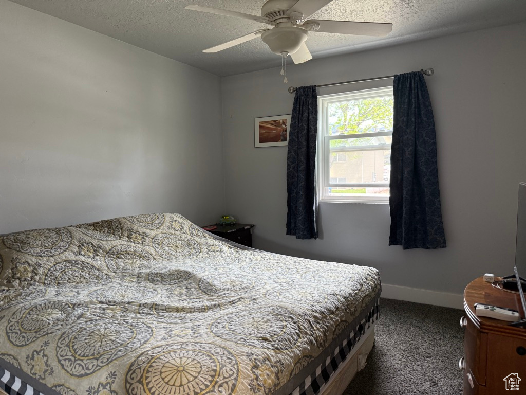 Carpeted bedroom with a textured ceiling, baseboards, and ceiling fan