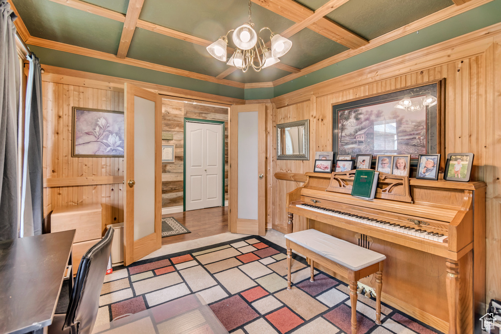 Entryway with wood walls, coffered ceiling, a chandelier, and crown molding