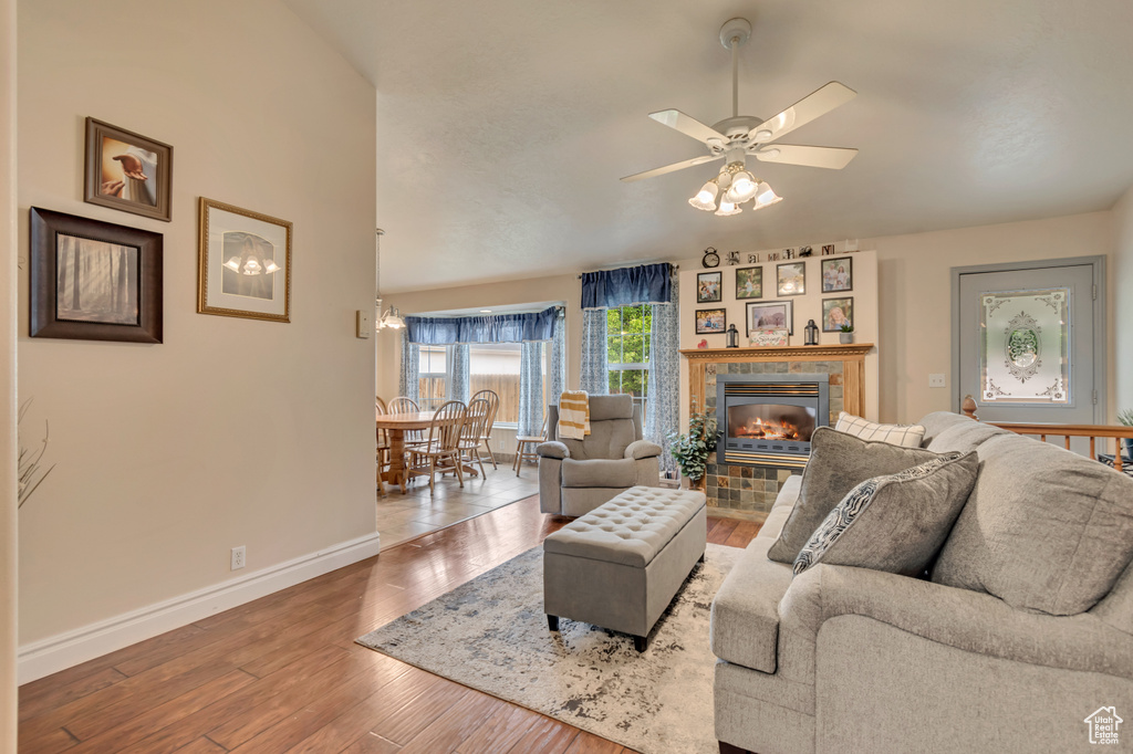 Living room with baseboards, wood-type flooring, a ceiling fan, and a fireplace