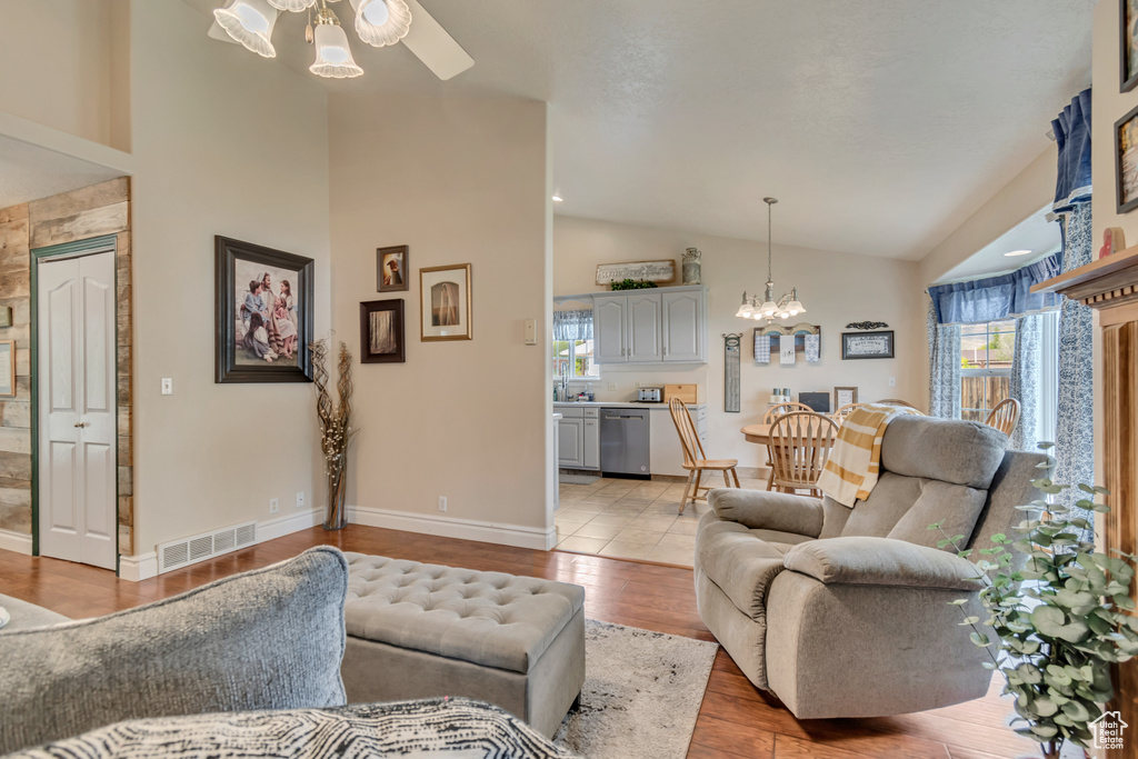 Living area featuring lofted ceiling, healthy amount of natural light, ceiling fan, a chandelier, and light wood-style floors