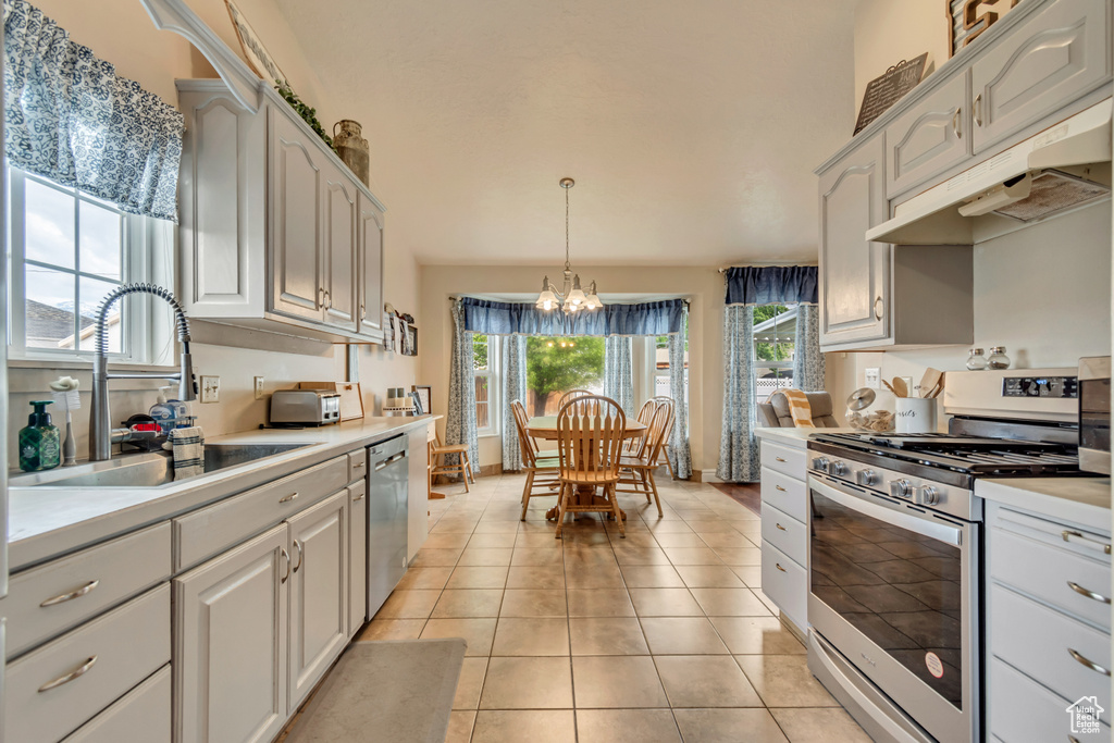 Kitchen featuring appliances with stainless steel finishes, under cabinet range hood, a chandelier, a sink, and light countertops