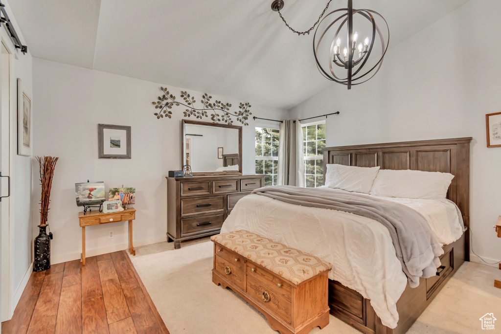 Bedroom with a chandelier, light wood finished floors, lofted ceiling, and baseboards