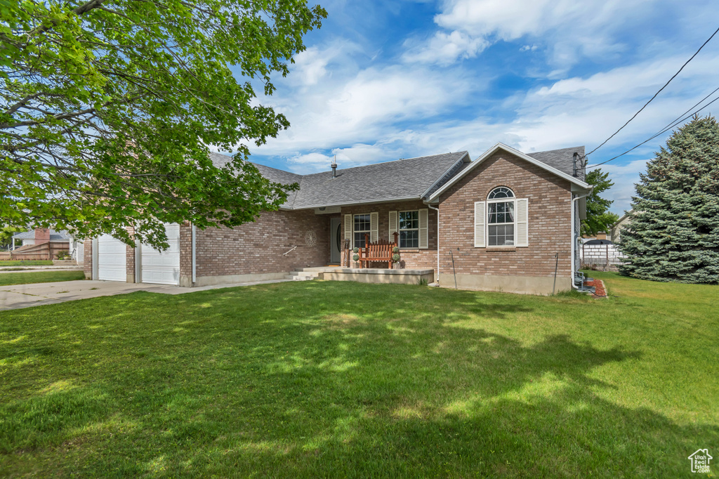 Single story home featuring brick siding, concrete driveway, a front lawn, and a garage
