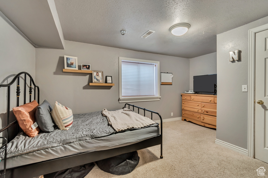 Bedroom featuring a textured ceiling, light carpet, and baseboards
