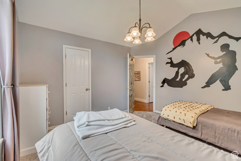 Carpeted bedroom featuring a chandelier, baseboards, and vaulted ceiling