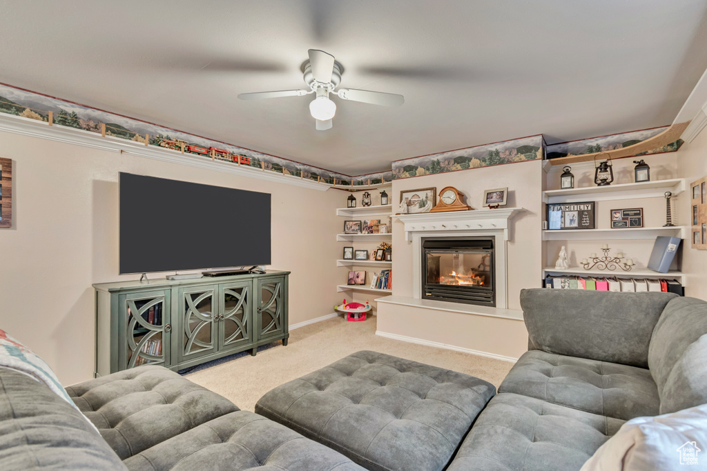 Living room with carpet, ceiling fan, and a glass covered fireplace