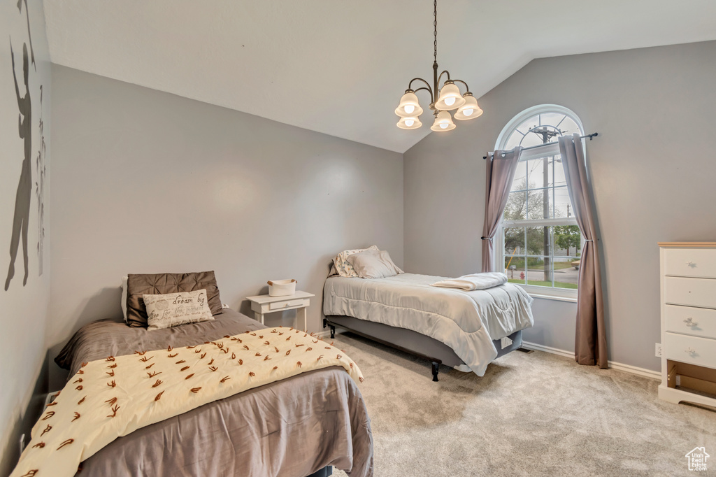 Carpeted bedroom featuring vaulted ceiling, a chandelier, and baseboards