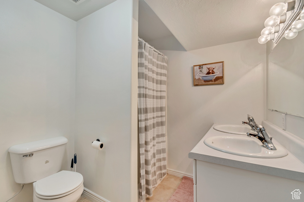 Bathroom featuring toilet, double vanity, a shower with curtain, and tile patterned flooring