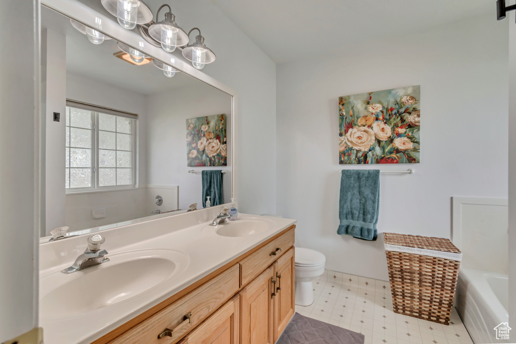Bathroom featuring a tub, toilet, double vanity, and tile patterned floors