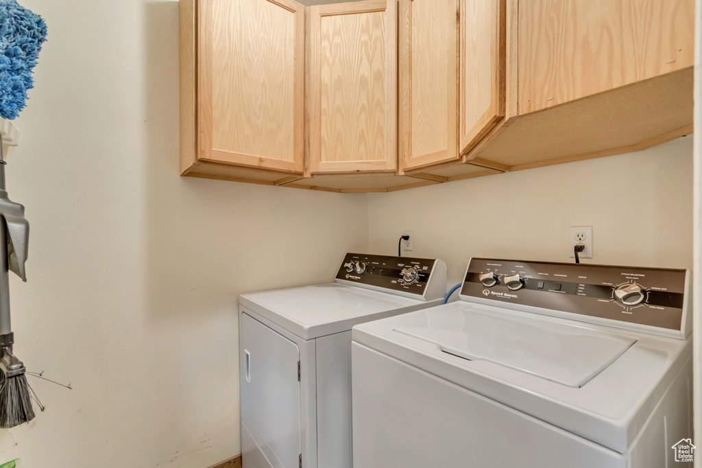 Clothes washing area featuring cabinet space and washer and clothes dryer