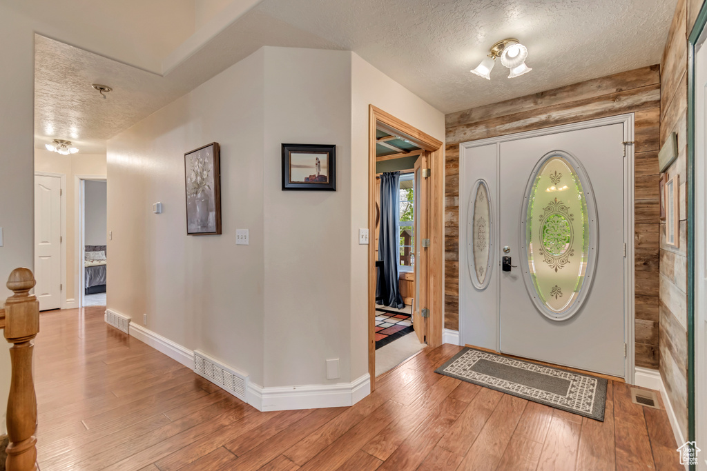 Foyer with a textured ceiling, light wood-type flooring, and baseboards