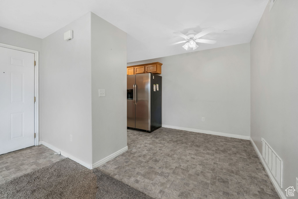 Carpeted empty room with a ceiling fan and baseboards