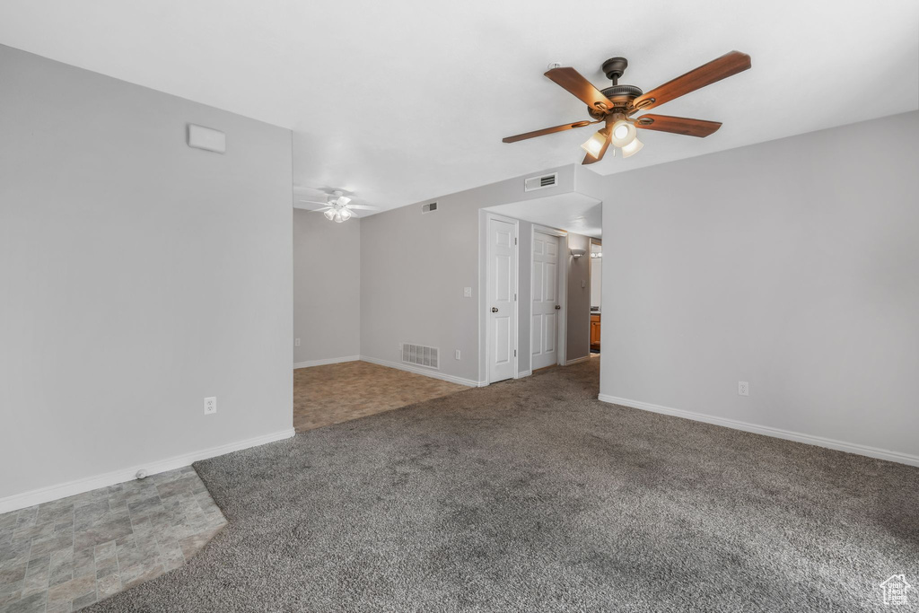 Empty room with a ceiling fan, carpet floors, and baseboards