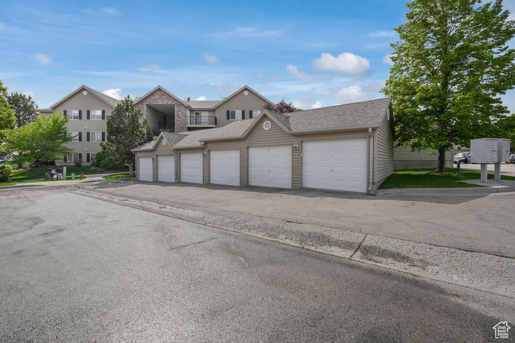 View of front of house featuring community garages and a shingled roof
