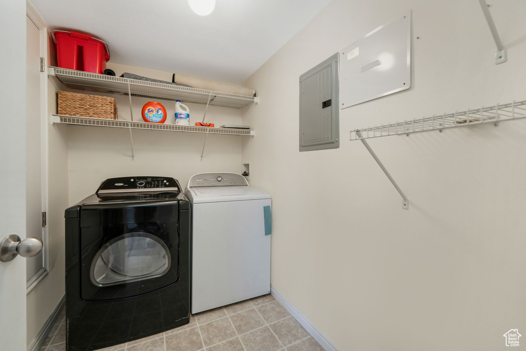 Laundry area featuring electric panel, washing machine and dryer, and baseboards