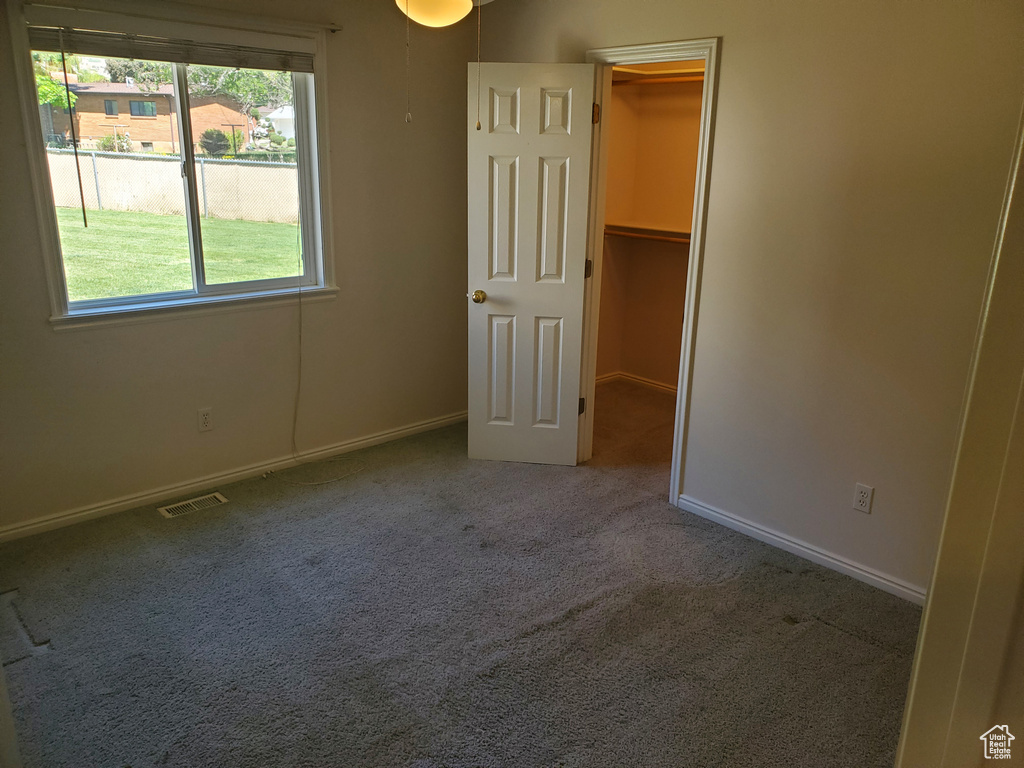 Unfurnished bedroom with a spacious closet, carpet flooring, and baseboards