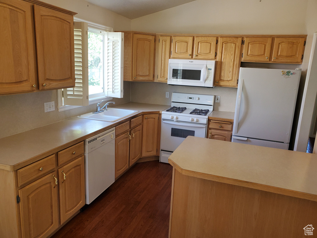Kitchen featuring white appliances, a sink, dark wood-style floors, light countertops, and lofted ceiling