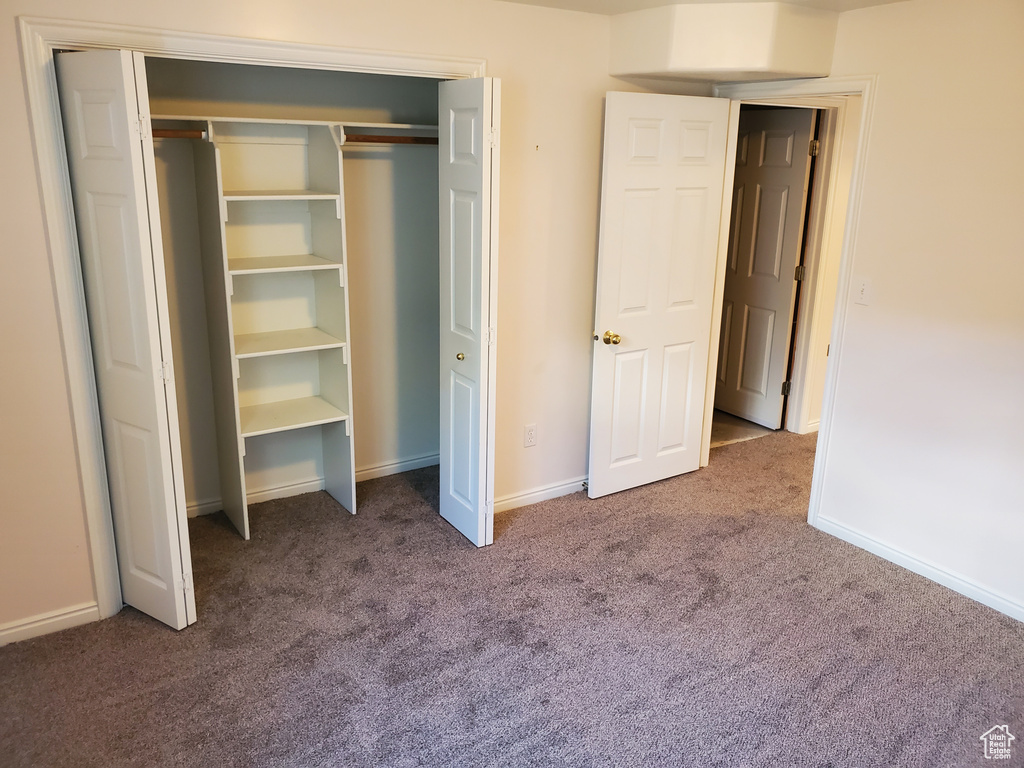 Unfurnished bedroom with carpet floors, baseboards, and a closet