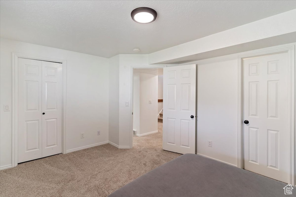 Unfurnished bedroom featuring light colored carpet, baseboards, and a closet