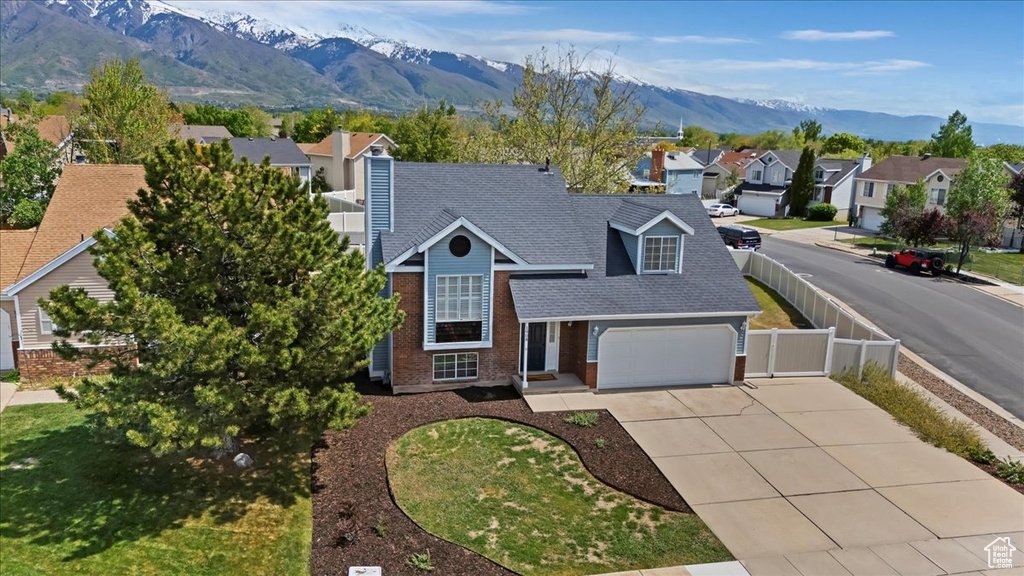 Traditional-style house with fence, concrete driveway, brick siding, and a residential view