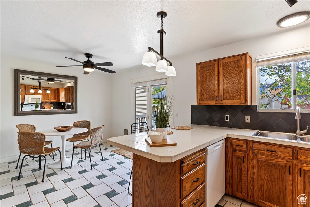 Kitchen featuring white appliances, a sink, a peninsula, and healthy amount of natural light