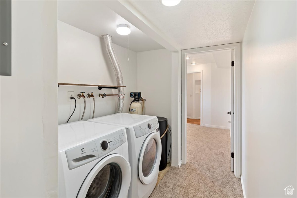 Laundry room with light colored carpet, independent washer and dryer, and baseboards
