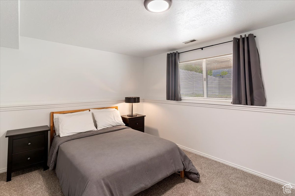 Bedroom featuring carpet floors, baseboards, and a textured ceiling