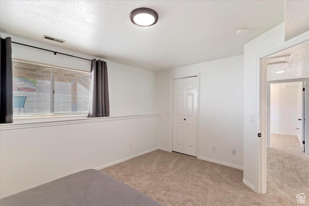 Unfurnished bedroom with carpet floors, a closet, baseboards, and a textured ceiling