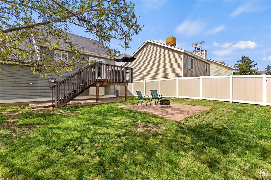Back of house featuring stairway, a deck, a patio area, an outdoor fire pit, and a chimney