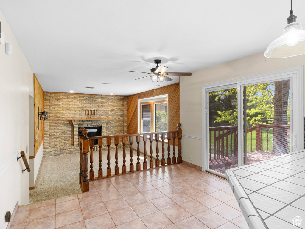 Empty room with ceiling fan, light tile patterned flooring, and a fireplace