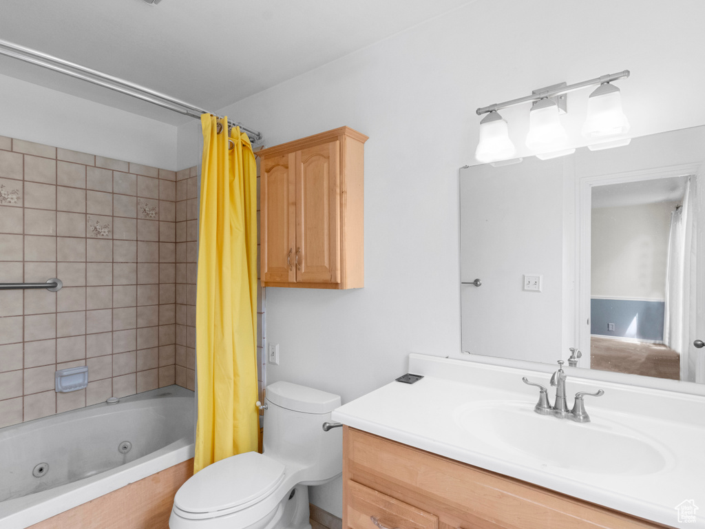 Bathroom featuring toilet, vanity, and a combined bath / shower with jetted tub