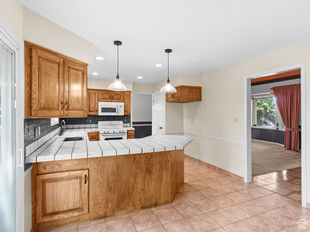 Kitchen with white appliances, a sink, tile counters, a peninsula, and recessed lighting