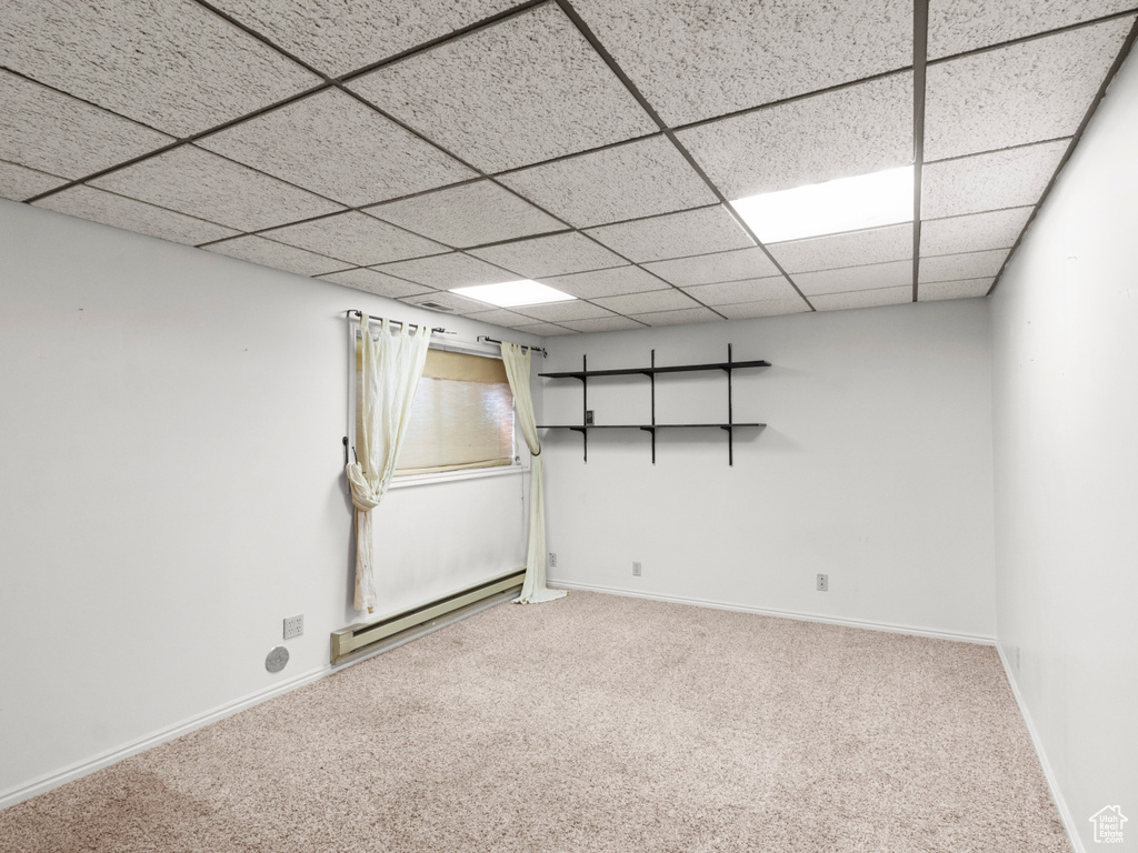 Basement with baseboard heating, carpet floors, a drop ceiling, and baseboards