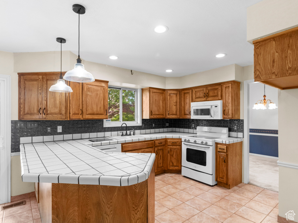 Kitchen with white appliances, a sink, brown cabinetry, and recessed lighting