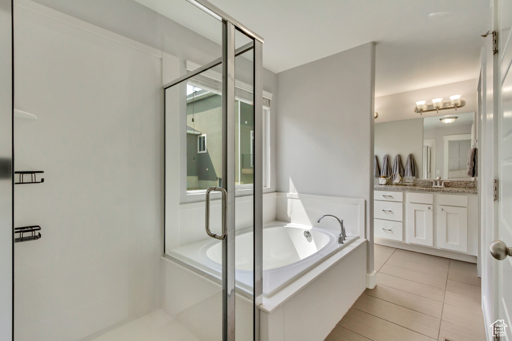 Full bath featuring a shower stall, tile patterned floors, a garden tub, and vanity