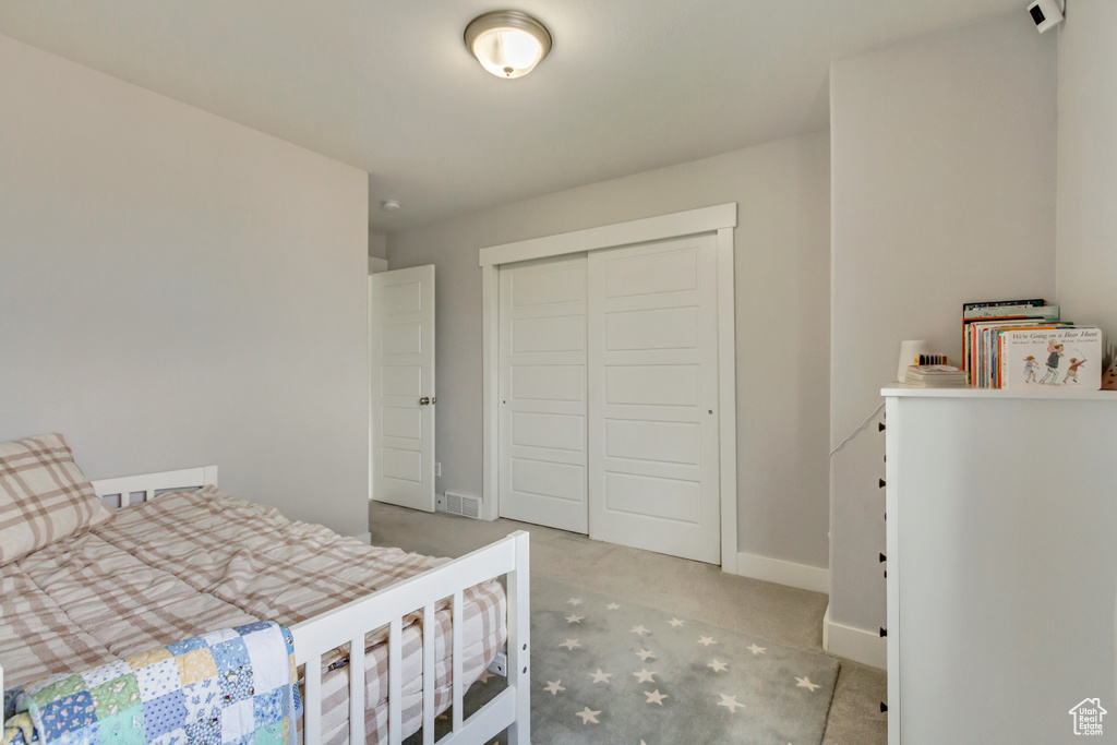 Carpeted bedroom featuring baseboards, a closet, and visible vents