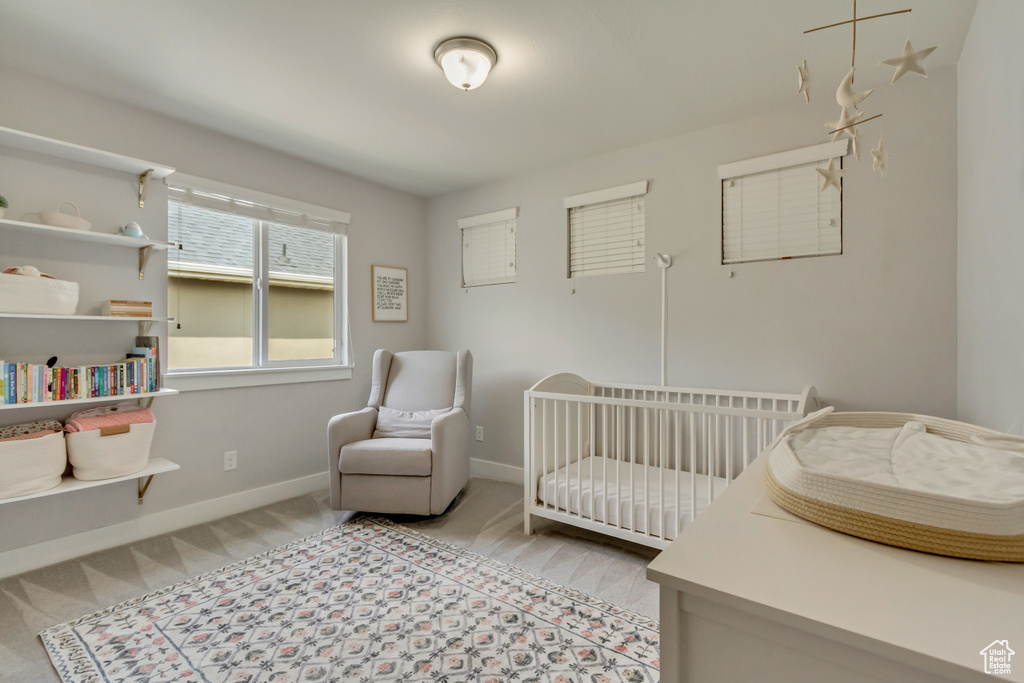 Bedroom featuring light colored carpet, baseboards, and a crib