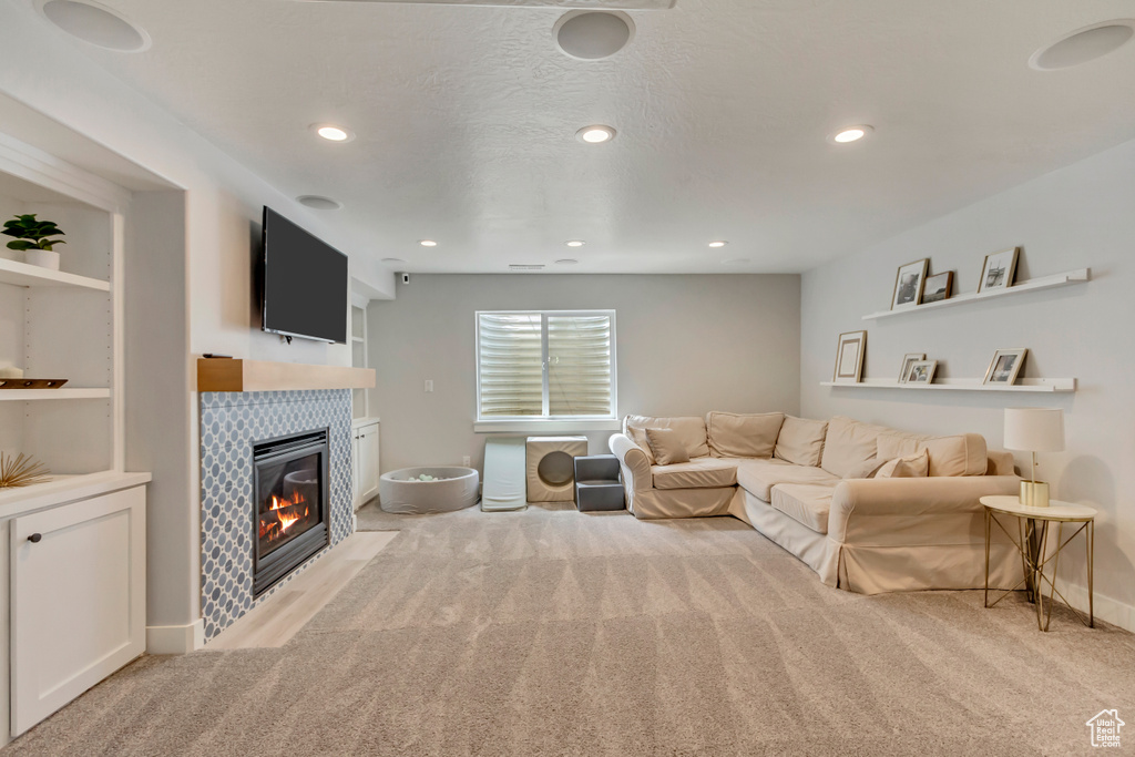 Living room featuring baseboards, a tiled fireplace, recessed lighting, and light colored carpet
