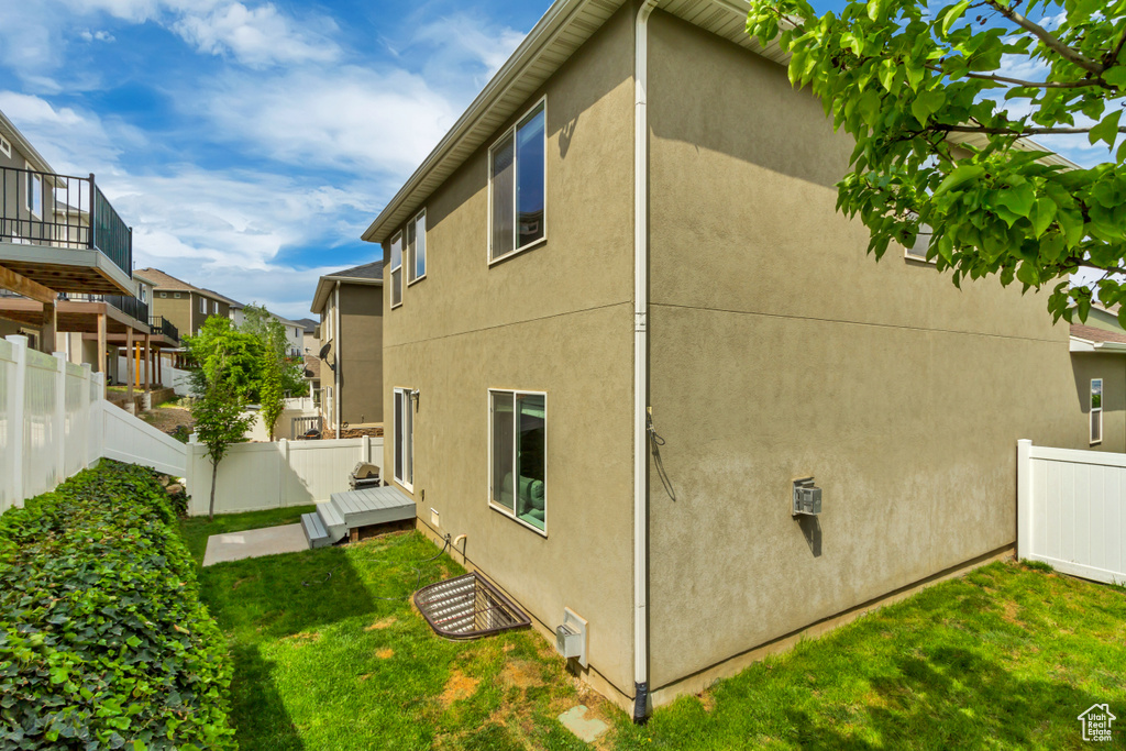 View of side of home featuring a yard, stucco siding, and fence