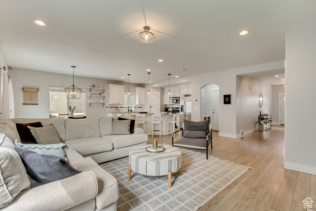 Living area with light wood-style flooring, baseboards, arched walkways, and recessed lighting