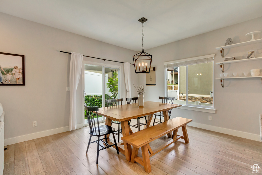 Dining space featuring light wood-style floors, baseboards, and a notable chandelier